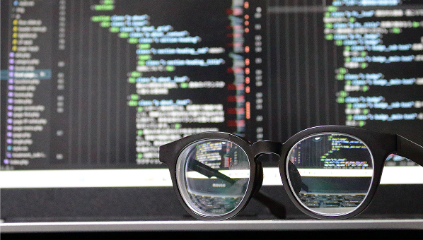 コーディング画面と眼鏡の写真